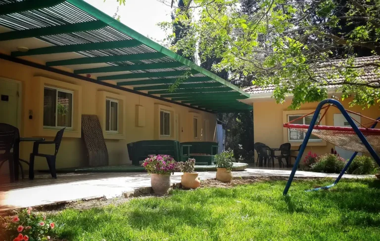 מרפסת מקורה וגינה עם נדנדה ליד החדרים