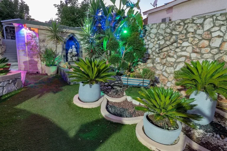 גינה מוארת עם עציצים וקיר אבן בבקצה הטבע