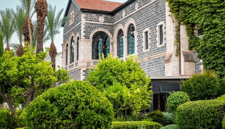 חזית אבן עם חלונות קשתיים וגינה ירוקה