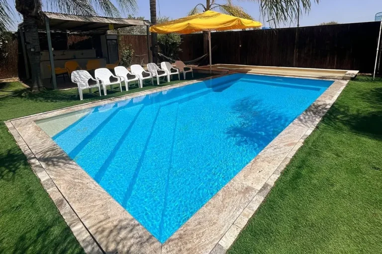 בריכה פרטית עם דשא ושמשיות בחצר של וילה בתלמים