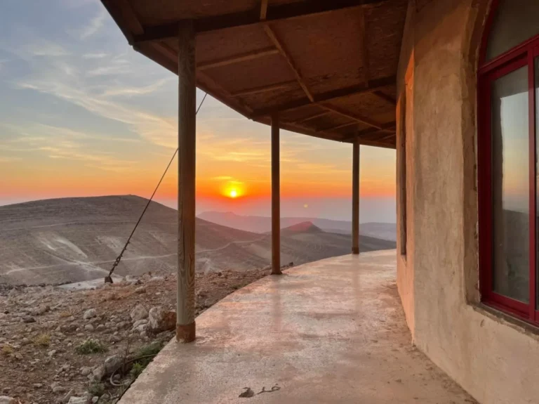 מרפסת מקורה עם עמודי עץ מול השקיעה